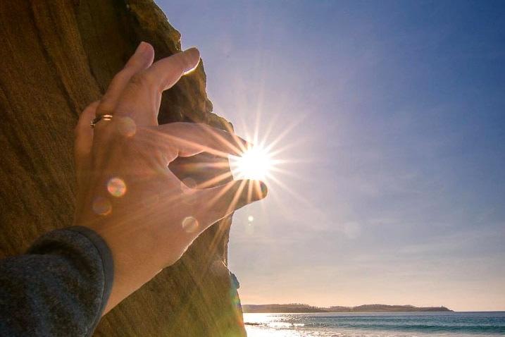 The Sun appears to be grasped between two fingertips.