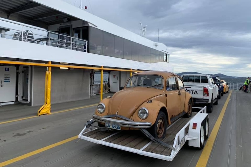 Photograph of a honeybrown old VW car on a trailer on a ferry.