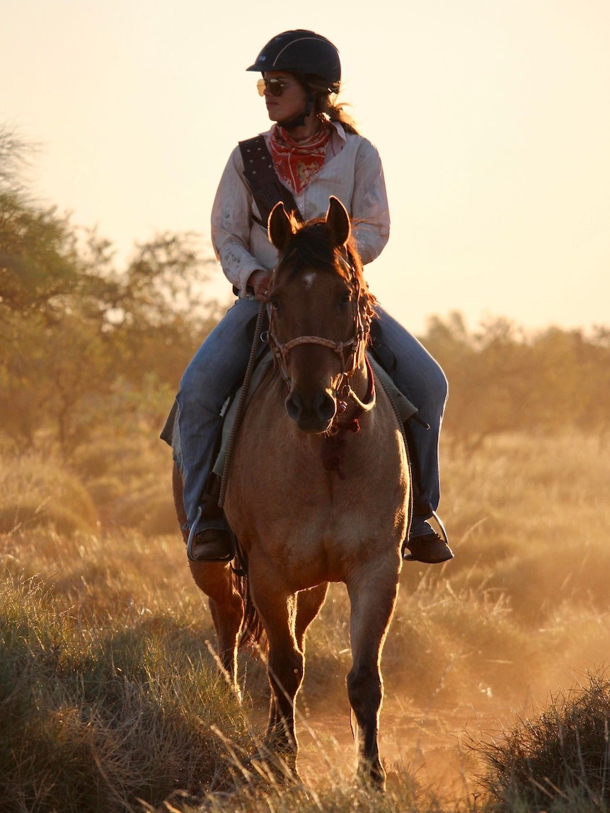 A women sits on horseback looking to her right