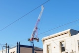 A crane can be seen above and behind shops on Bridge Road, Richmond.