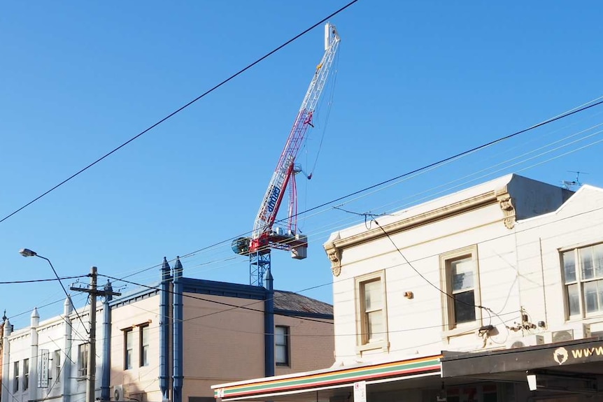 A crane can be seen above and behind shops on Bridge Road, Richmond.