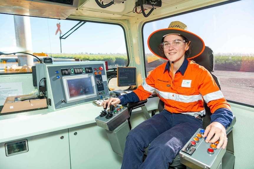 a young woman sits in the control area of a cane train