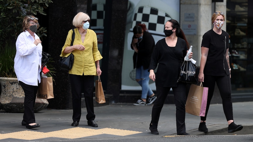 Shoppers walk wearing face masks in a retail district of Auckland