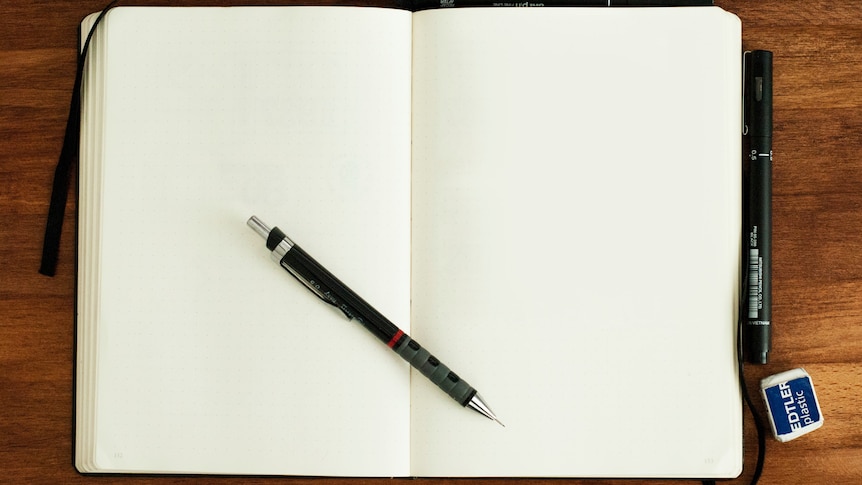 A blank notebook on a wooden surface with a pen in the middle