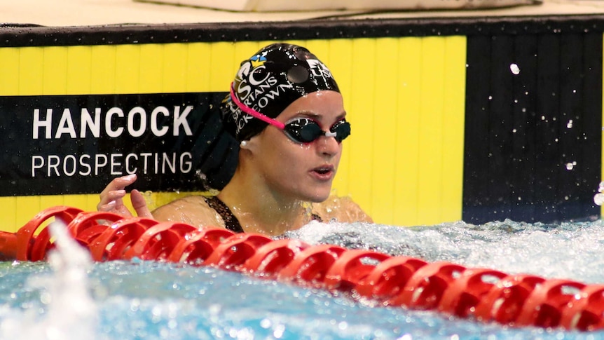 A goggles-wearing swimmer sits in her lane after winning a race at the Australian national titles.