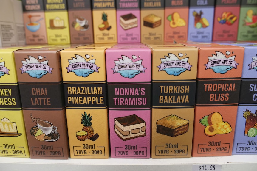 Boxes of flavoured vape juice products sit on a shop shelf.