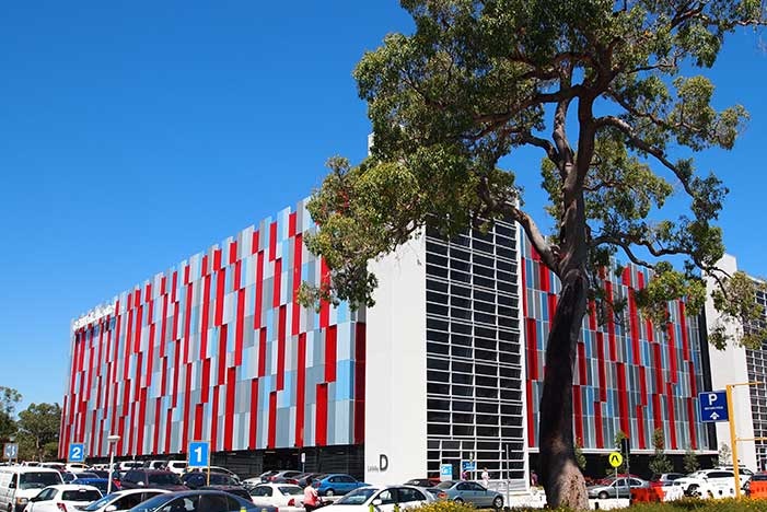 A wide shot of the Queen Elizabeth II Medical Centre with a carpark and tree in the foreground.