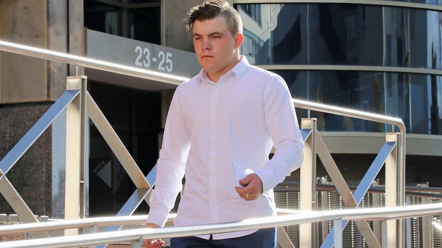 A young man walks down a ramp in front of a building with the numbers 23-25 signed out front