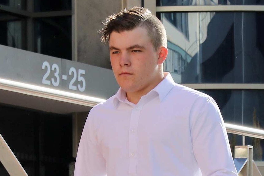 A young man walks down a ramp in front of a building with the numbers 23-25 signed out front