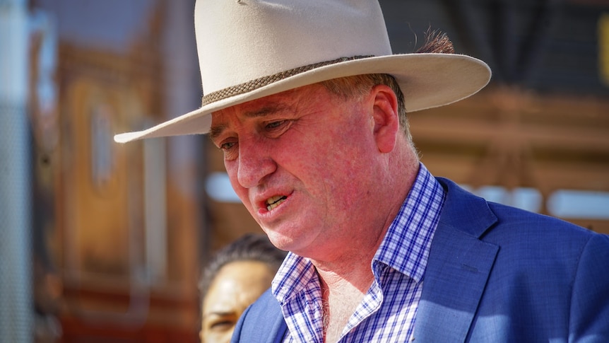 Barnaby Joyce, wearing a 10-gallon hat and a light-coloured suit, speaking with the sun on his face.