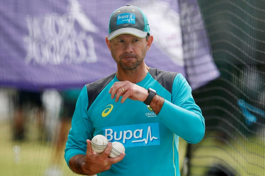 Ricky Ponting carries a number of cricket balls while wearing Australian training gear.