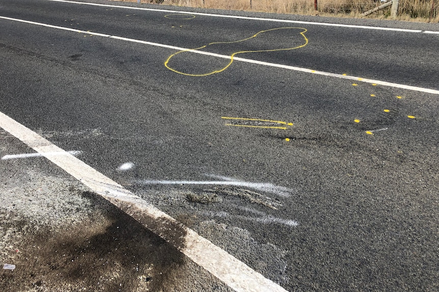 A close up of a road with oil and yellow markings on it.