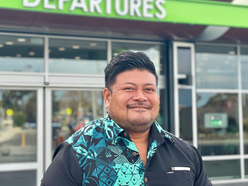 An islander man stands in front of an airport window