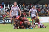 A group of football players embracing on the ground after a try