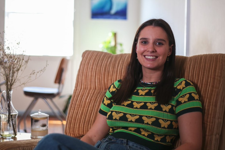 Hayley smiles sitting on a couch.