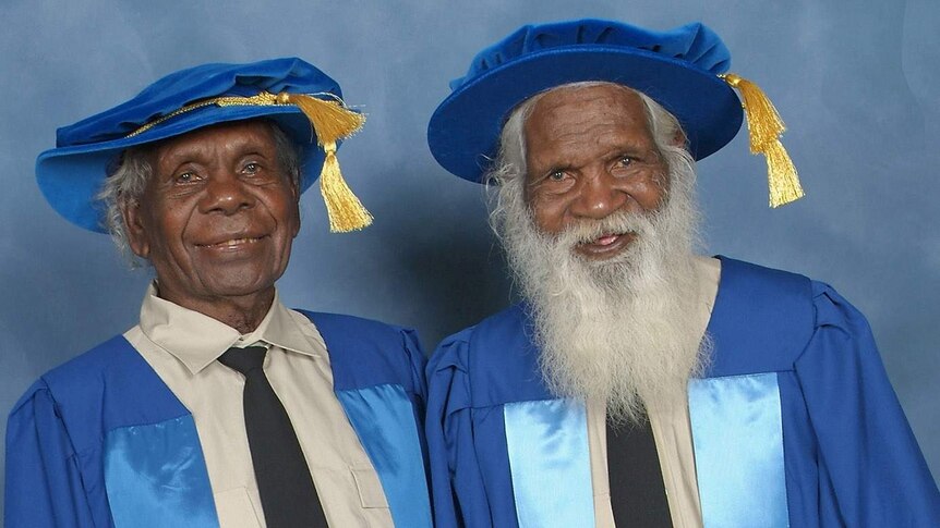 Two Indigenous Elders wear blue gowns at a university event