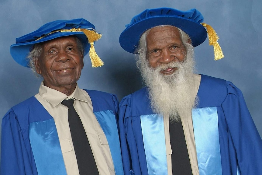 Two Indigenous Elders wear blue gowns at a university event