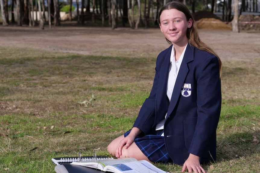 High school student Olivia Condon sits on the grass outside her school.