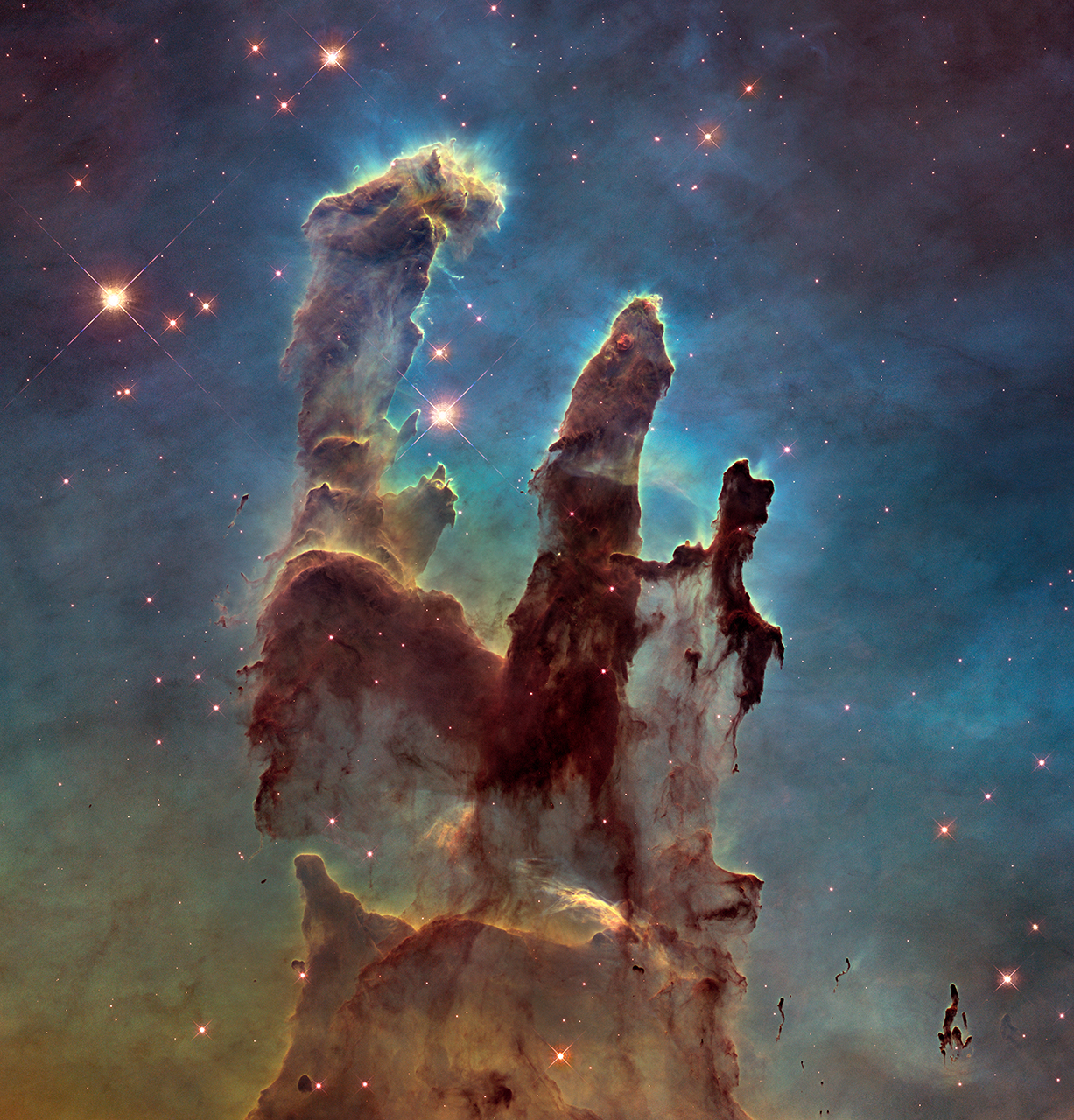 A detailed image of the Pillars of Creation, showing reddish purple dust clouds on a greenish-black background.