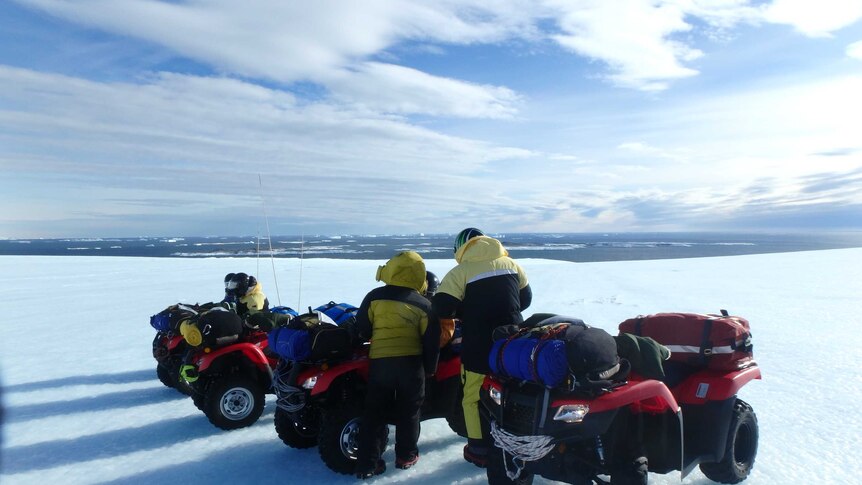 Staff on quad bikes stop on the snow to check their map