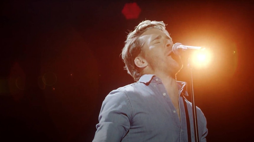 Actor and singer Hugh Sheridan singing into a microphone.