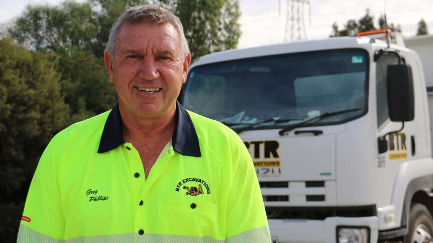 A man in a fluoro shirt in front of a truck