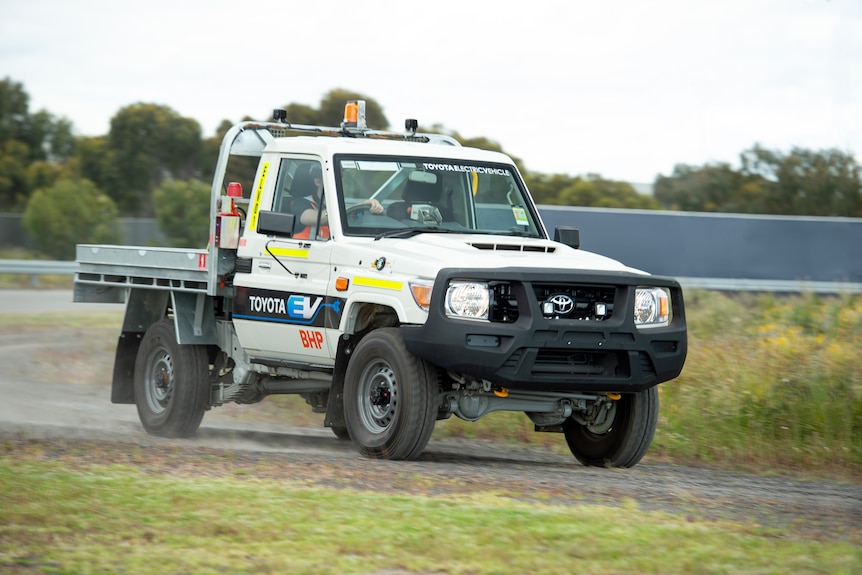 an electric land cruiser ute driving on a country road