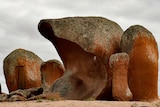 Large red rocks stick out of the ground in a dark and cloudy day.