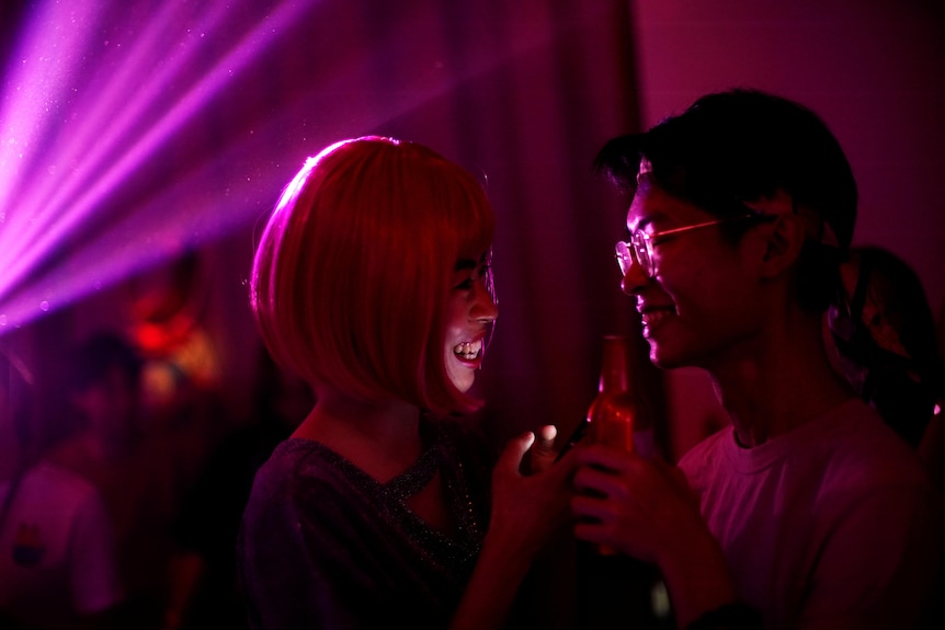 Two young people look at each other in a party