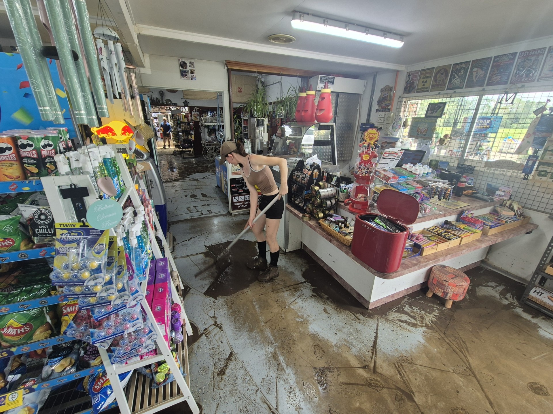 Una mujer barre barro en una tienda.