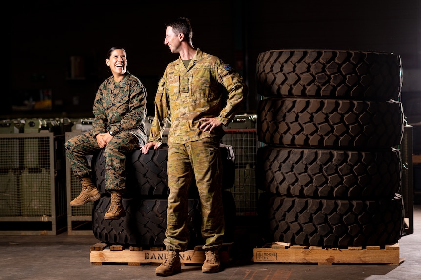  A woman and man wearing army uniform smiling at each other in a dark room 