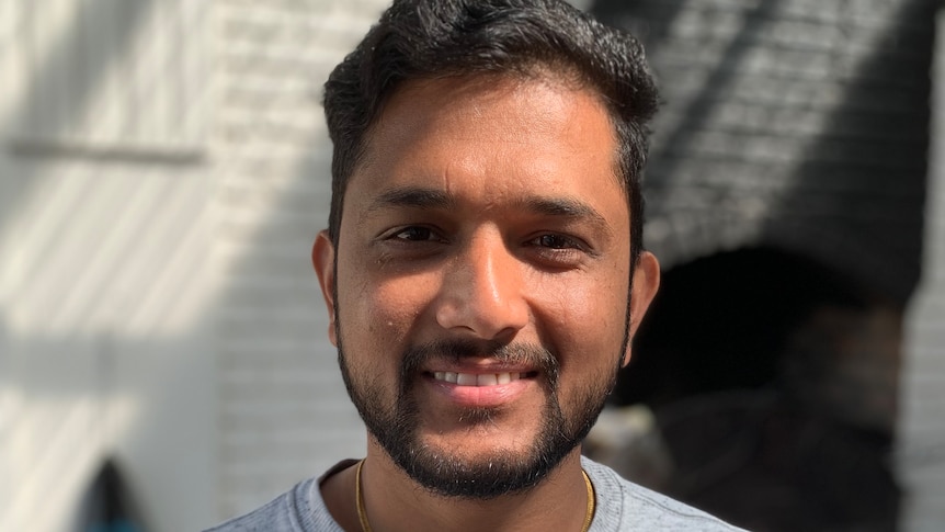 Former aged care worker Pratik Sigdel smiles in soft dappled sunlight.