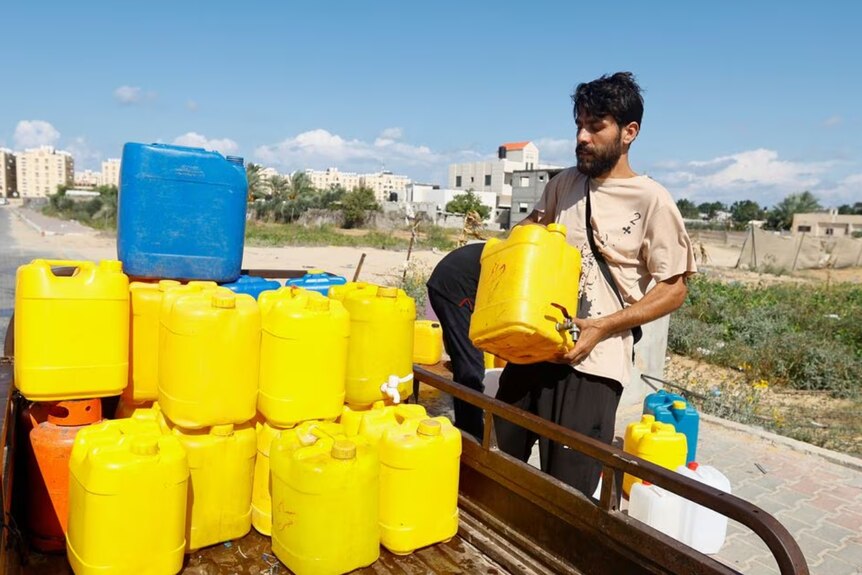 A man standing next to dozens of bright yellow water containers