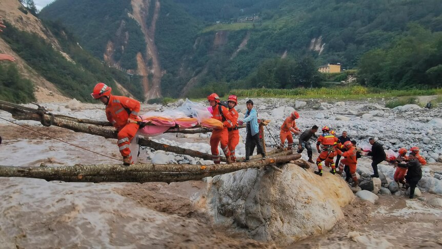 Rescuers transfer earthquake survivors across a river