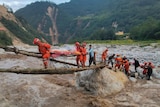 Rescuers transfer earthquake survivors across a river