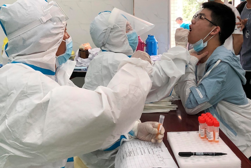 Lucrătorii din domeniul sănătății din echipamentele individuale de protecție iau tampoane nasale pentru COVID-19