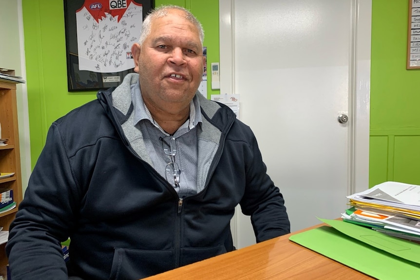 a man sitting behind a desk smiling