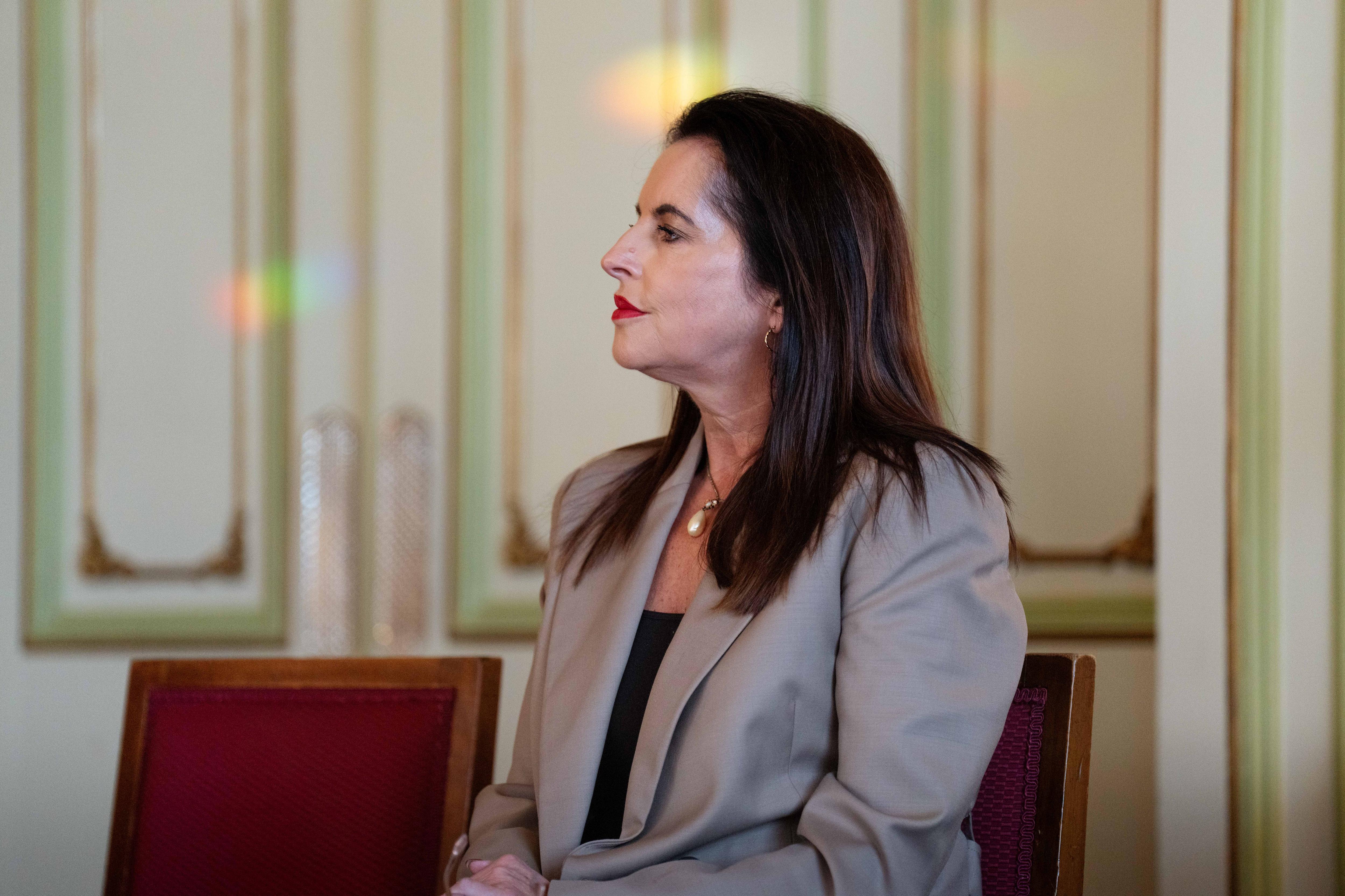 A woman looks off to the side while seated.