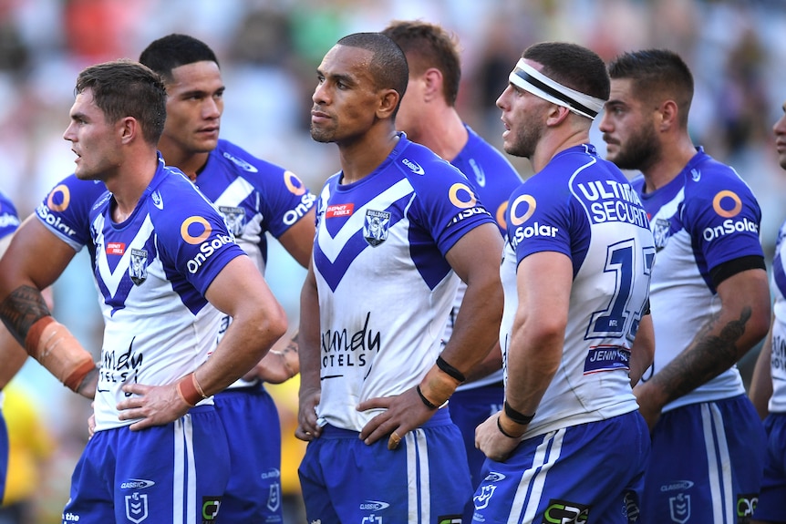 Rugby league players standing with their hands on their hips after losing a match.