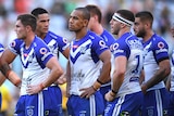 Rugby league players standing with their hands on their hips after losing a match.