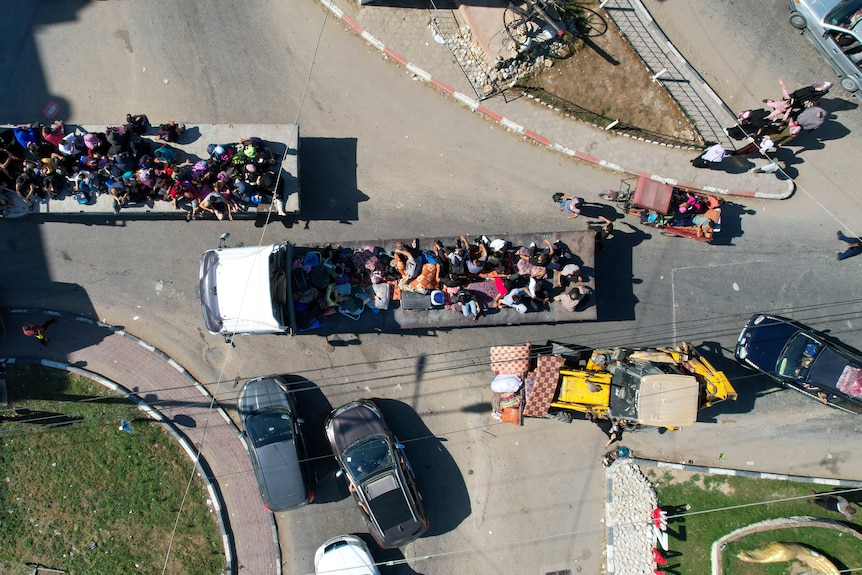 Birds-eye view of people travelling in the back of trucks and on foot