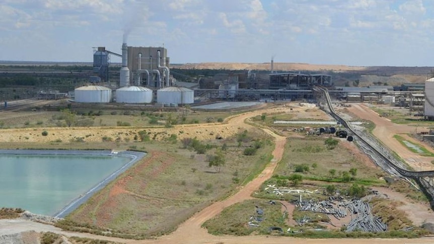 An aerial view of a mine with lots of large silos and roads, in the middle of the outback