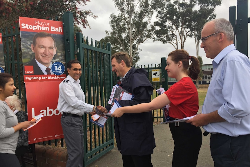 Bali handing out campaign material to a man.