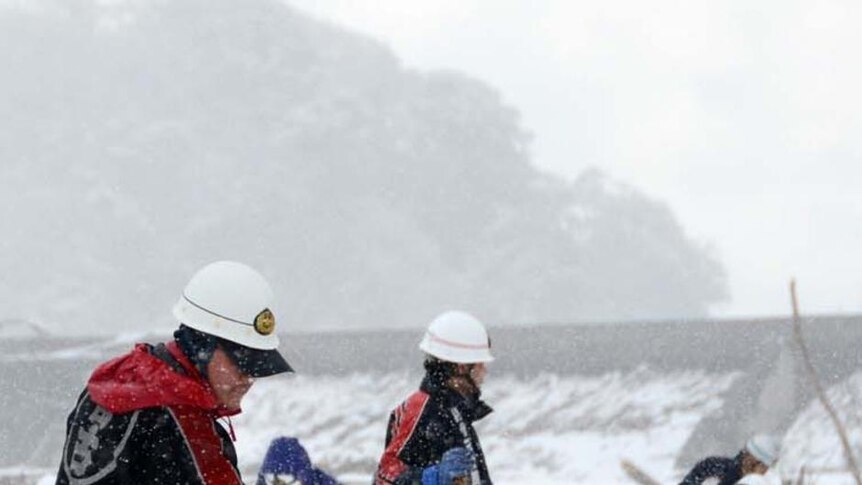 Japanese rescue workers search through snow