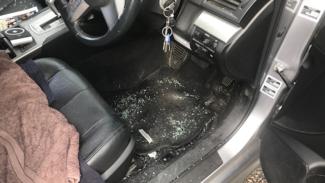 Broken glass scattered on the floor of a front seat of a car