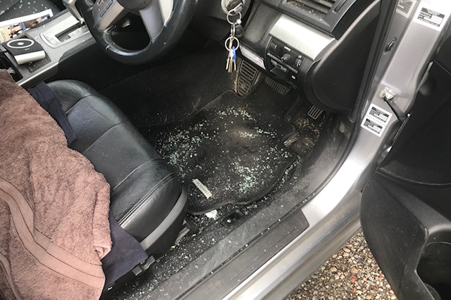 Broken glass scattered on the floor of a front seat of a car