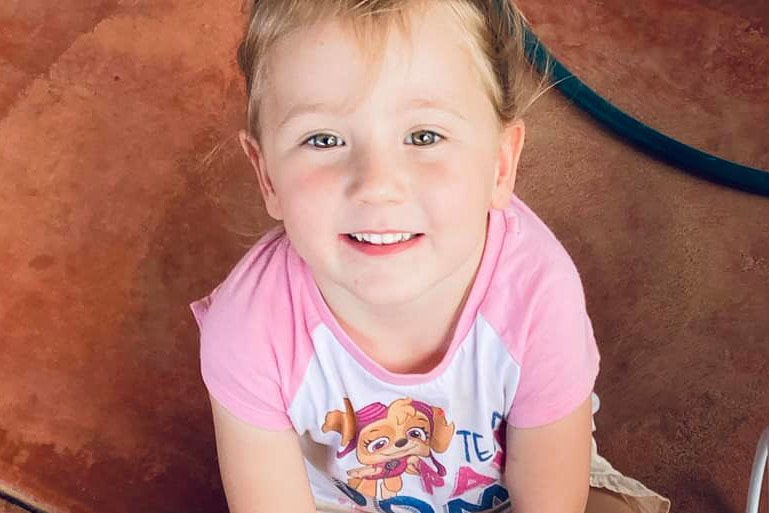 A close-up shot of a smiling Cleo Smith sitting on the floor looking up at the camera.