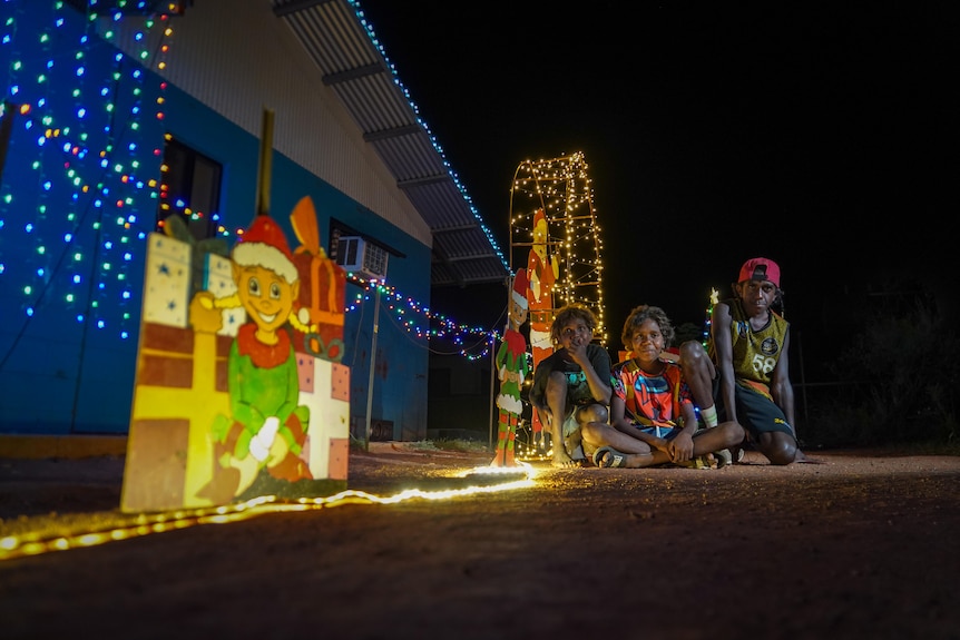 Kids sit under Christmas lights