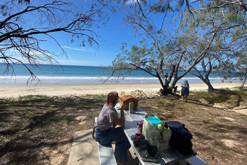 Wide shot of a family at a picnic table overlooking the beach