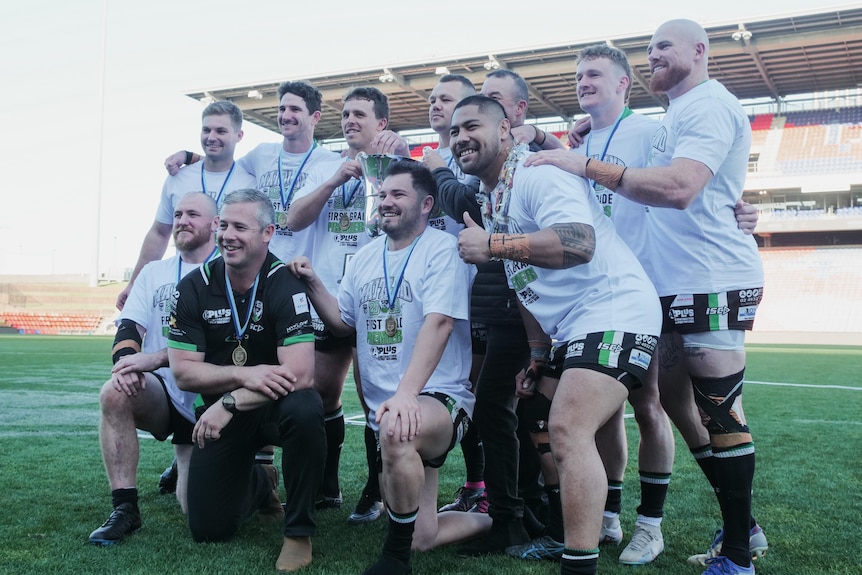 a group of rugby league players posing with their premiership cup